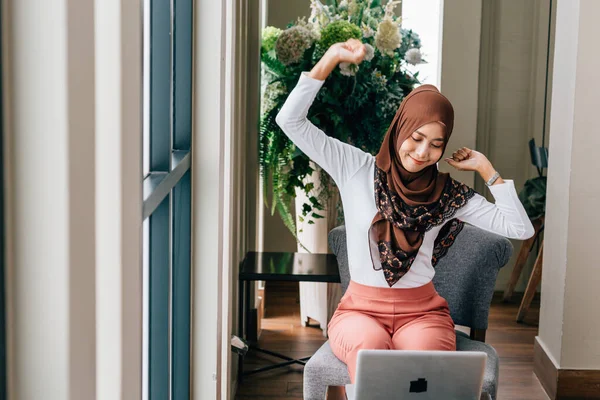 Muslim female with laptop stretching body — Stock Photo, Image