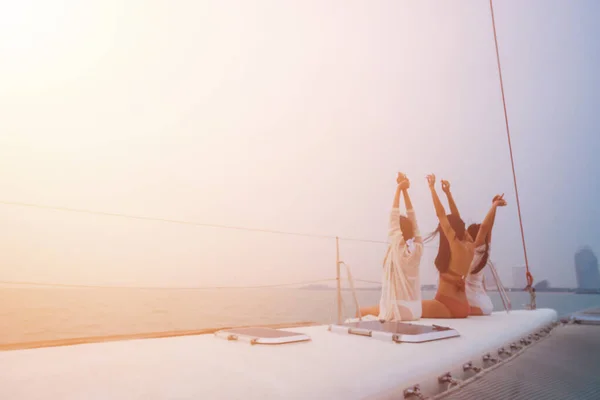 Três jovens mulheres alegres de biquíni sentadas no barco e admirando a vista do mar — Fotografia de Stock