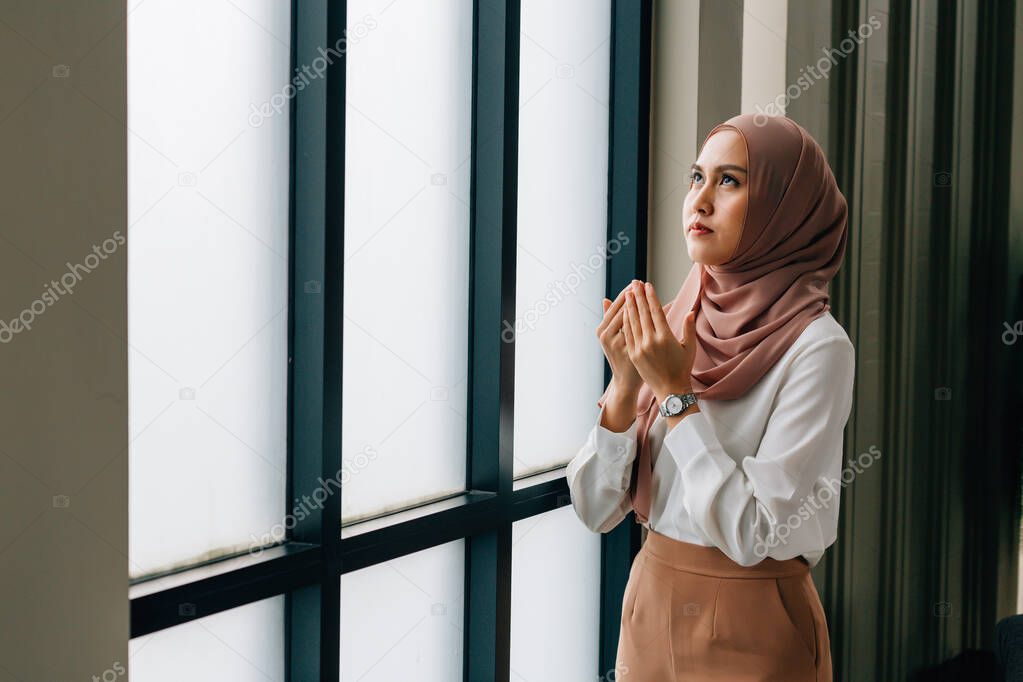 Islamic woman praying near window