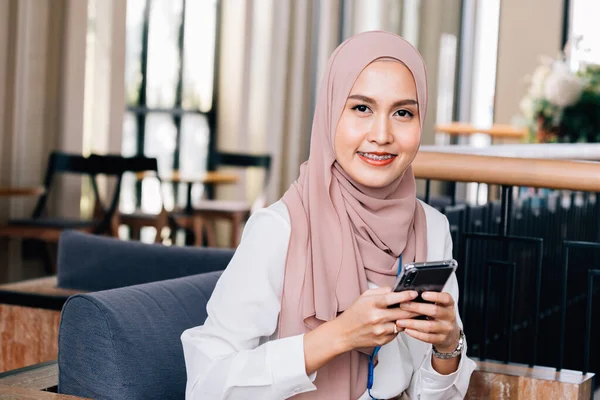 Счастливая мусульманка использует смартфон в кафе — стоковое фото