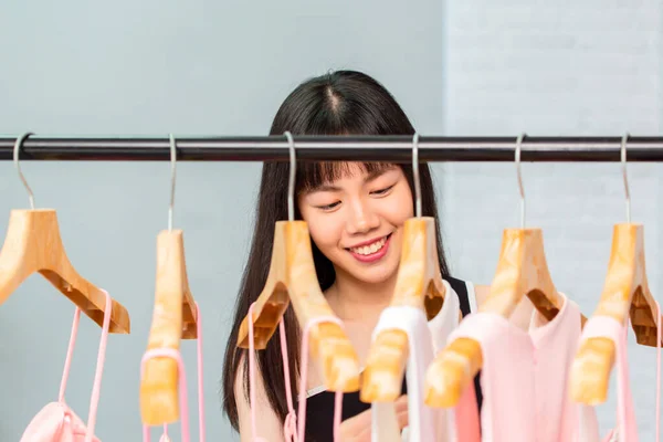 Smiling ethnic woman browsing through rack of clothes — Stock Photo, Image