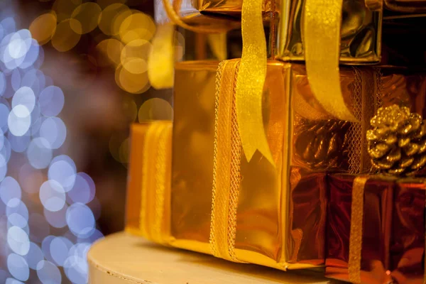 Altın renkli hediyeler üst üste yığılmış, altın sarısı arkaplanlı. — Stok fotoğraf