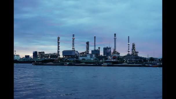Planta de refinería de petróleo junto al río en el crepúsculo — Vídeos de Stock