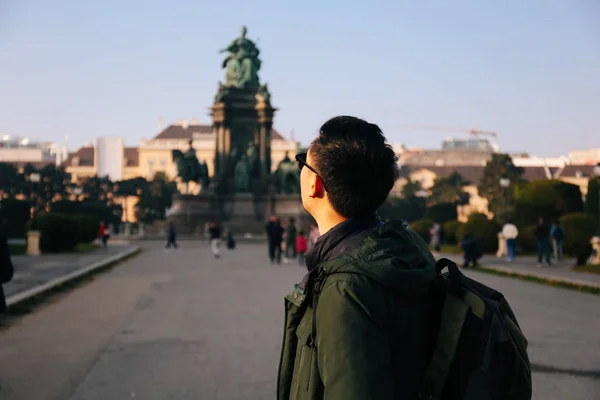 Back view portrait of Asian male tourist backpacker carrying a bag in Maria Theresa Monument in Vienna, Austria — Stock Photo, Image