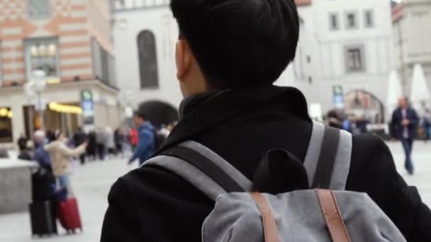 Young Asian man tourist traveling in city centre in Europe. Male backpacker walking in Marienplatz square, Munich, Germany — Stok video