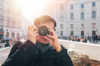 Viyana, Avusturya, Avrupa 'daki Hofburg Sarayı yakınlarında elinde kamerayla fotoğraf çeken genç bir Asyalı turist. Avrupa 'nın ünlü turistik mekanı.