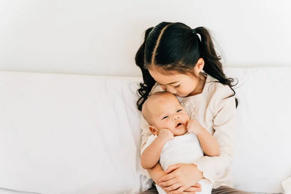 Azji dziecko przytula noworodka na łóżku — Zdjęcie stockowe