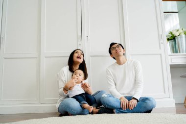 Happy Asian family sitting on floor and looking up