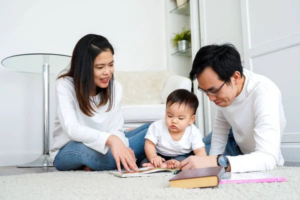 Padres jóvenes leyendo libro para hijo pequeño —  Fotos de Stock