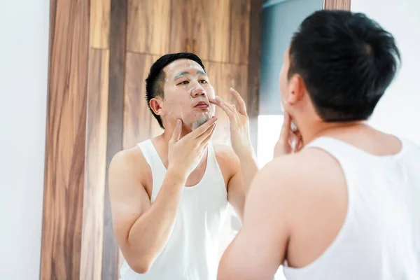 Jovem asiático cara usando máscara facial no banheiro — Fotografia de Stock