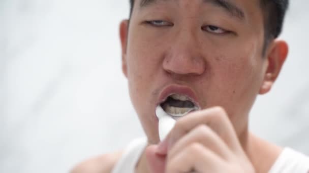 Asyalı adam elektrikli diş fırçası kullanarak diş temizliyor — Stok video