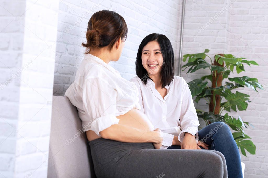 Young Asian pregnant woman talking with another female expectant at antenatal class in hospital