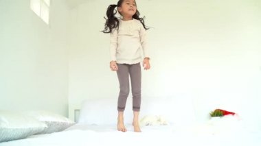 Heyecanlı Asyalı çocuk yatakta zıplıyor 