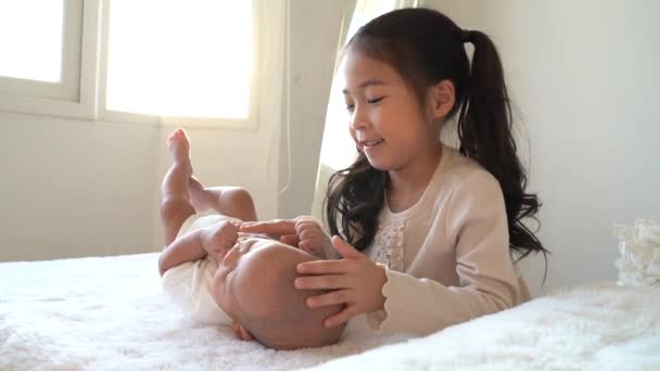 Ασιατική οικογένεια της χαριτωμένης αδελφής αγγίζουν νεογέννητο αγοράκι αδελφό στο κρεβάτι — Αρχείο Βίντεο