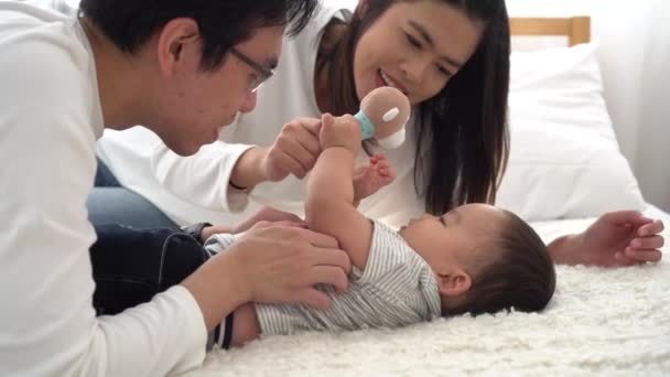 Семья молодого азиатского отца нежно целует своего маленького мальчика на животе с женой — стоковое видео