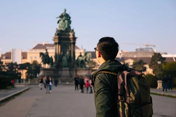 Achteraanzicht portret van Aziatische mannelijke toerist backpacker met tas in Maria Theresa Monument in Wenen, Oostenrijk, Europa — Stockfoto