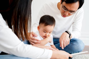 Young parents reading book for little son