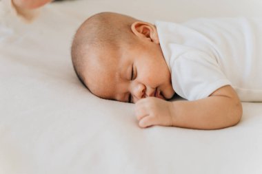 Evde karnının üstünde uyuyan yeni doğmuş bir bebek. Asyalı çocuk uyukluyor