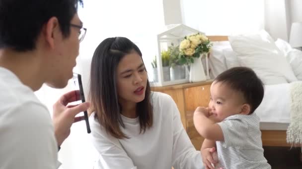 Bebé asiático chico con madre viendo vídeo en el teléfono inteligente y riendo — Vídeos de Stock