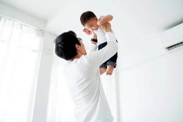Asijský otec zvedá svého malého vlastního syna létat ve vzduchu — Stock fotografie