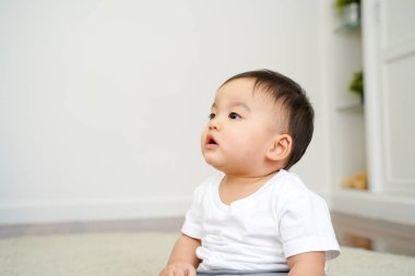 Asian boy sitting on the floor alone at home next to bed