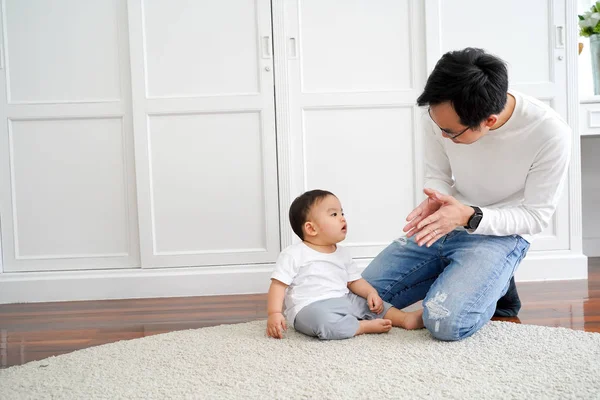 Feliz asiática familia de joven padre jugando juegos y aplaudiendo manos con bebé niño en casa —  Fotos de Stock