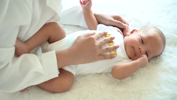 Милый азиатский новорожденный мальчик лежит на кровати, а мама руки на животе в помещении — стоковое видео