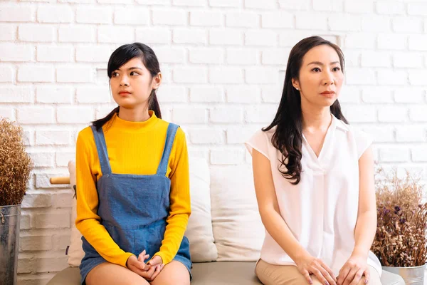 Недовольные азиатские женщины сидят на диване — стоковое фото