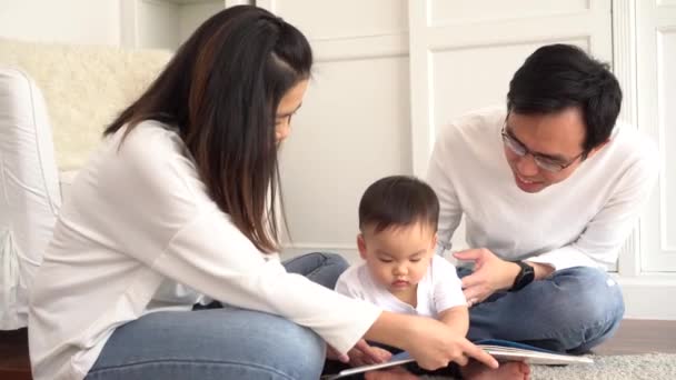 Padres jóvenes leyendo libro para hijo pequeño — Vídeo de stock