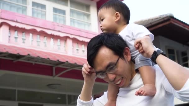 Asiático padre dando un paseo a cuestas para pequeño hijo en frente de la casa — Vídeos de Stock