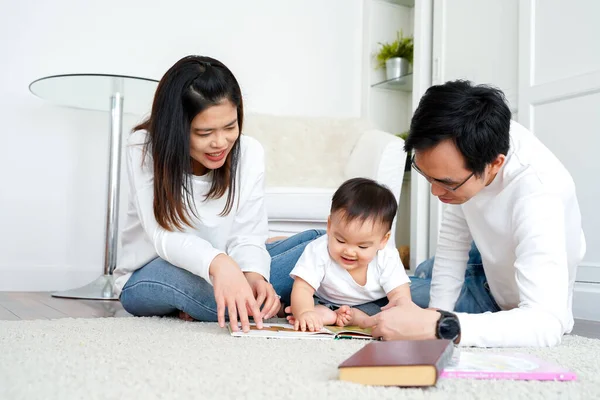 Padres jóvenes leyendo libro para hijo pequeño —  Fotos de Stock