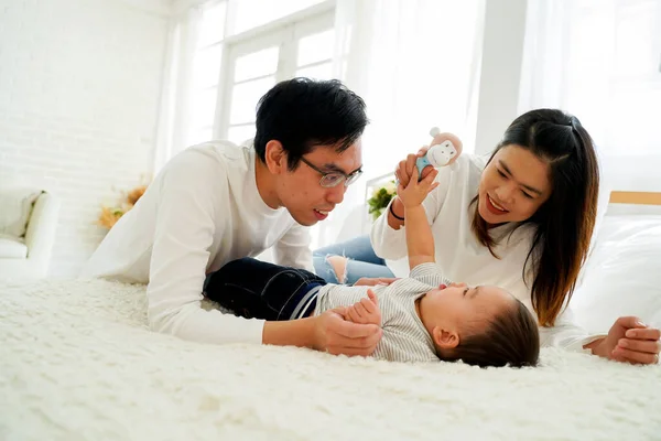 Азиатская семья отца и матери играют в игрушечную куклу со своим сыном на кровати дома — стоковое фото