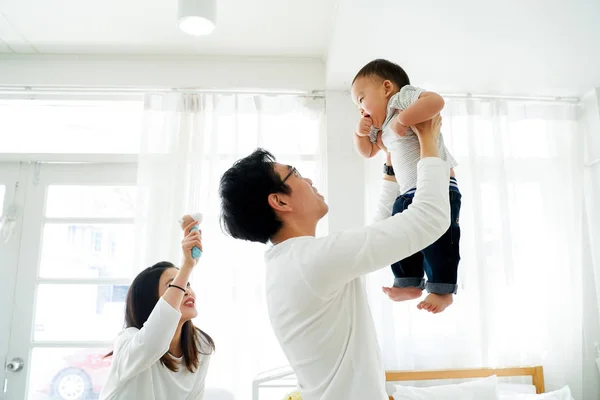 Asijský otec a matka zvednout jejich malý vlastní syn létat ve vzduchu se smíchem — Stock fotografie