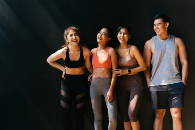 Mutlu gülümseyen adam ve kadınlar spor salonunda konuşarak eğleniyorlar. Antrenmandan sonra spor salonunda dinlenen bir grup genç..