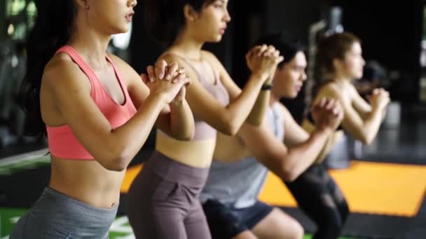 Grupo de jóvenes atléticos asiáticos en ropa deportiva haciendo sentadilla y haciendo ejercicio en el gimnasio. Entrenamiento intenso y concepto de estilo de vida saludable — Vídeo de stock