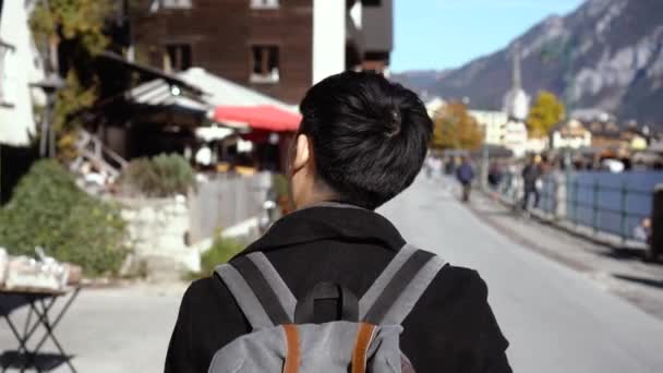 Молодой азиат покупает туристические товары и смотрит на сувениры в озере Халлстатт в Зальцкаммергуте во время поездки в Австрию — стоковое видео
