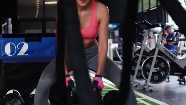 Ásia misto feminino fisiculturista praticando crossfit batalha cordas com movimento no fitness ginásio — Vídeo de Stock