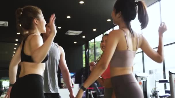 Le man och kvinna gör händer tillsammans i gym. Grupp av ungdomar gör hög fem gest i gymmet efter träningen. Glad lyckad träningsklass efter träning — Stockvideo