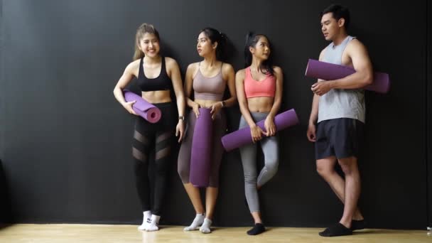 Glücklich lächelnde Männer und Frauen, die in Turnhallen in die Kamera schauen. Gruppe junger Asiaten entspannt sich nach dem Training im Fitnessstudio mit schwarzem Hintergrund — Stockvideo