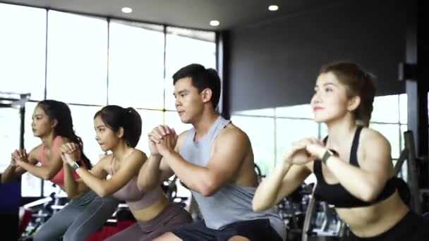 Grupo de jóvenes atléticos asiáticos en ropa deportiva haciendo sentadilla y haciendo ejercicio en el gimnasio. Entrenamiento intenso y estilo de vida saludable — Vídeos de Stock