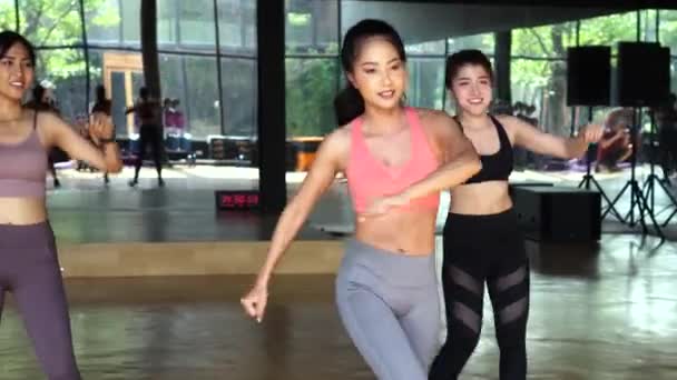 Donne di fitness che hanno una lezione di ballo latino insieme in palestra. Gruppo di giovani donne sportive che mettono le mani in alto — Video Stock