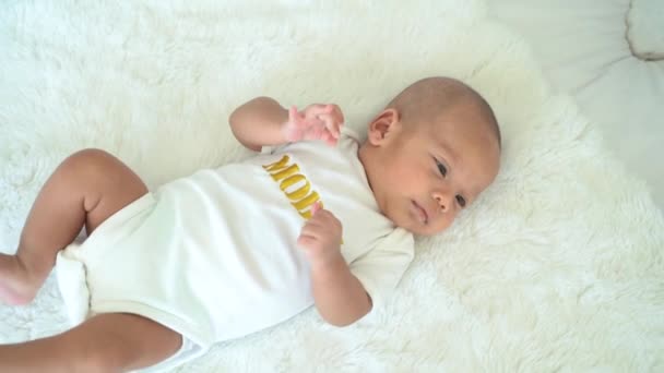 Спокойный азиатский новорожденный ребенок лежит на кровати — стоковое видео