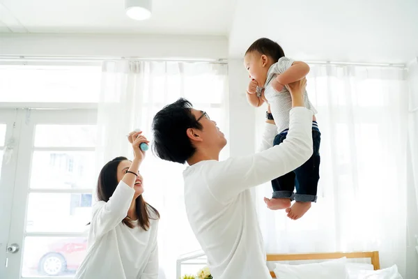 Azji ojciec i matka podnosząc ich mały własny syn w górę latający w powietrzu ze śmiechem — Zdjęcie stockowe
