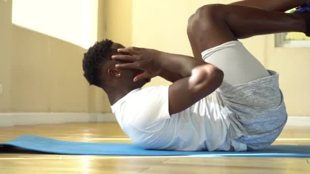 Joven hombre afroamericano haciendo ejercicio de sentada en la esterilla de yoga en el gimnasio. Modelo de fitness masculino que realiza crunch en el gimnasio — Vídeo de stock