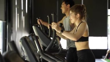 Attractive Asian fitness woman using elliptical trainer at the gym. Healthy and weight loss lifestyle