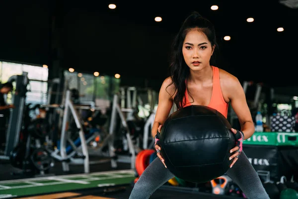 Vastberaden en serieuze actieve Aziatische sportvrouw kraken met medicijnbal tijdens het sporten in fitness club — Stockfoto