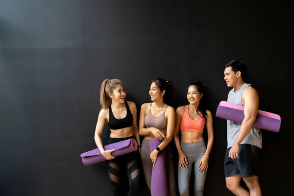 Szczęśliwy uśmiechnięty mężczyzna i kobieta dobrze się bawią rozmawiając na siłowni. Grupa młodych ludzi relaksujących się na siłowni po treningu. — Zdjęcie stockowe