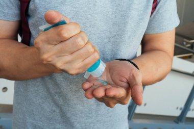 Man washing hands and applying alcohol gel to clean and get rid of germ, bacteria at train station
