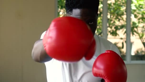 Sportowiec Afroamerykanin w czerwonych rękawiczkach bokserskich atakujący podczas treningu. mężczyzna bokser wykrawanie w siłownia — Wideo stockowe