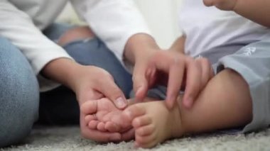 Anne bebeğin ayaklarına masaj yapıyor.